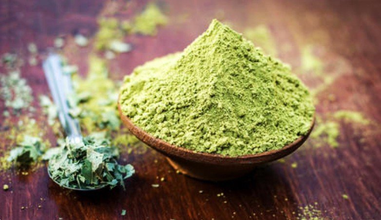 Cuenco de henna en polvo y hojas frescas